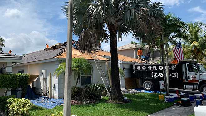 Tiger Team Roofing workers working on a new roof cleaning up debris in Coral Springs, FL
