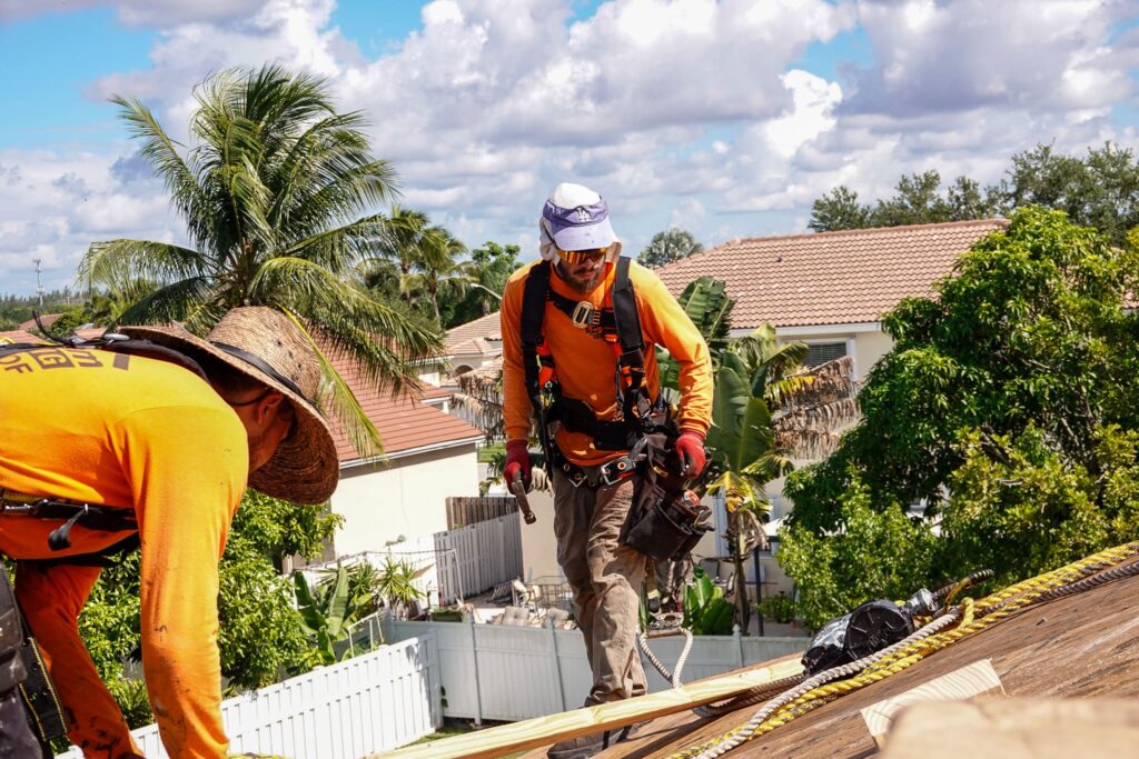Two roofing crew members working safely on a residential roof in South Florida.