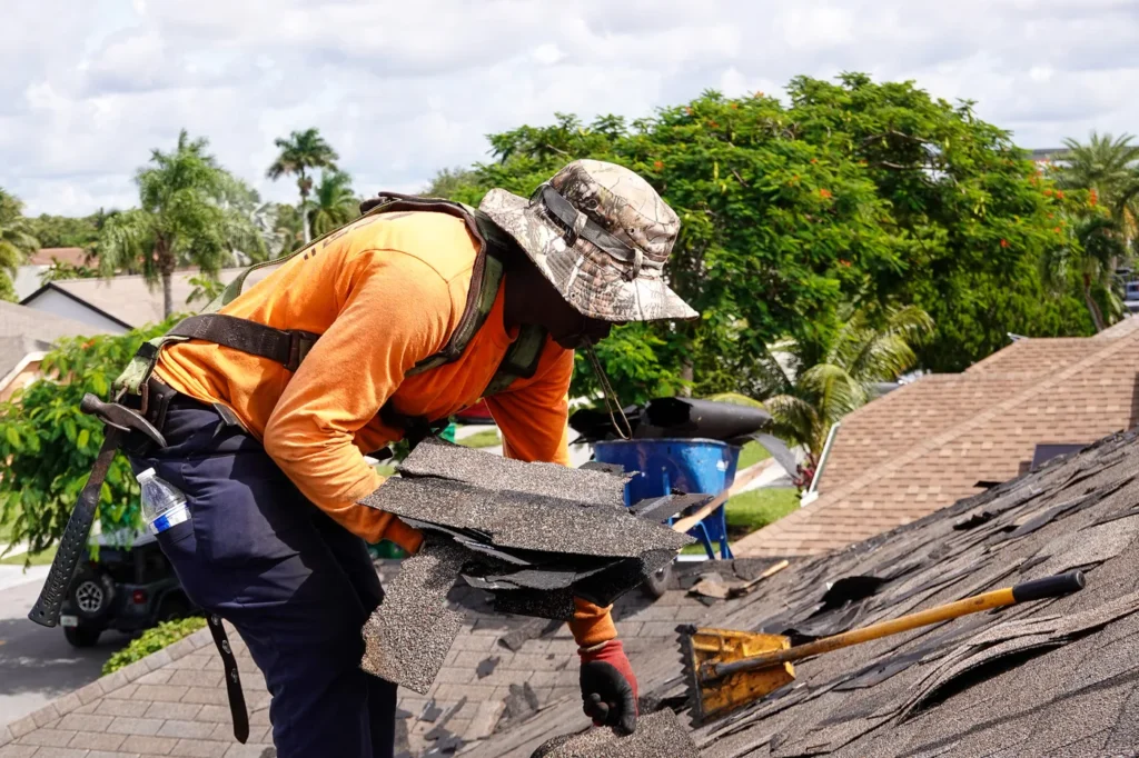 Roofer removing damaged shingles during a roof tear-off in South Florida