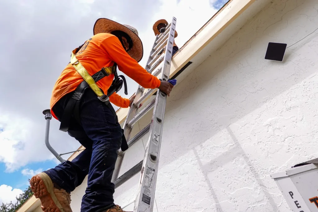 Tiger Team Roofing technician climbing a ladder for a roof maintenance visit in Fort Lauderdale